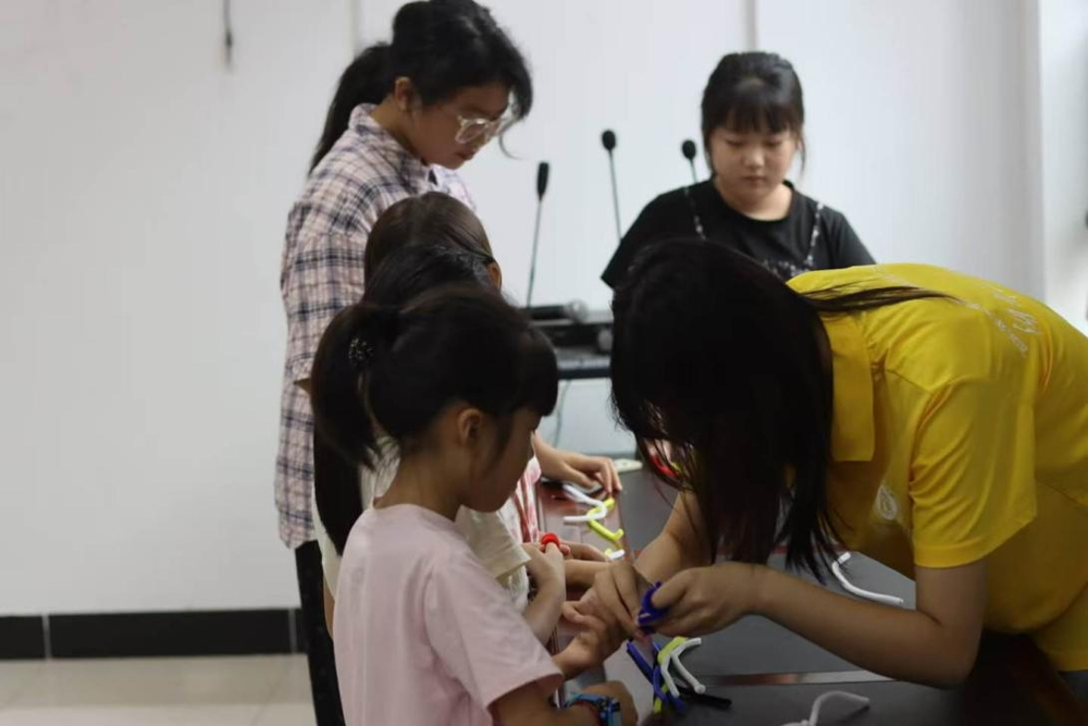 图1：图为志愿者指导孩子们用扭扭棒制作安全主题手工