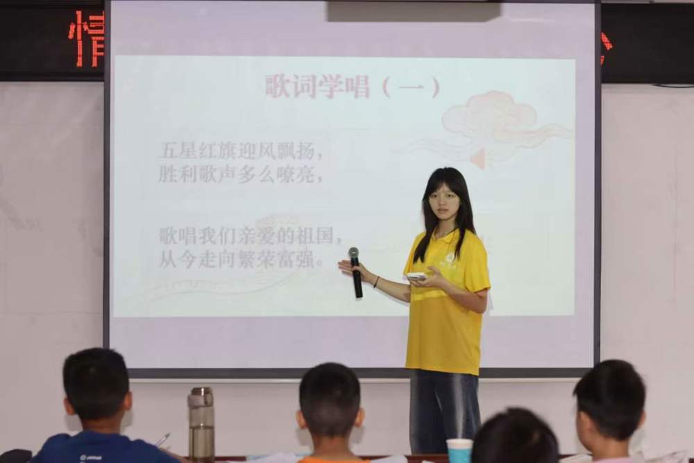 图2：图为授课成员细心教导孩子们唱歌