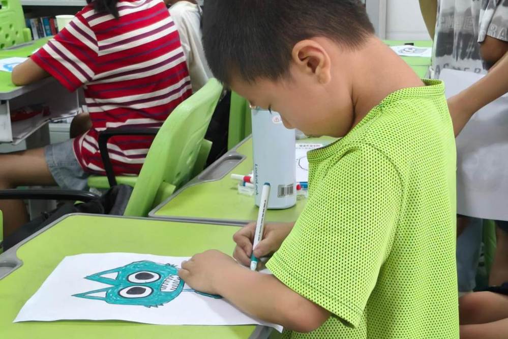 图2：图为孩子独自专注完成创意美术作品