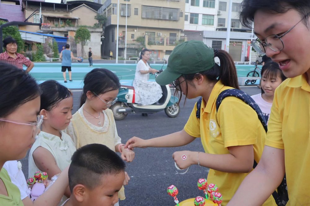 图2：图为队员现场为参与游戏的小朋友分发棒棒糖、橡皮擦、小扇子等礼品