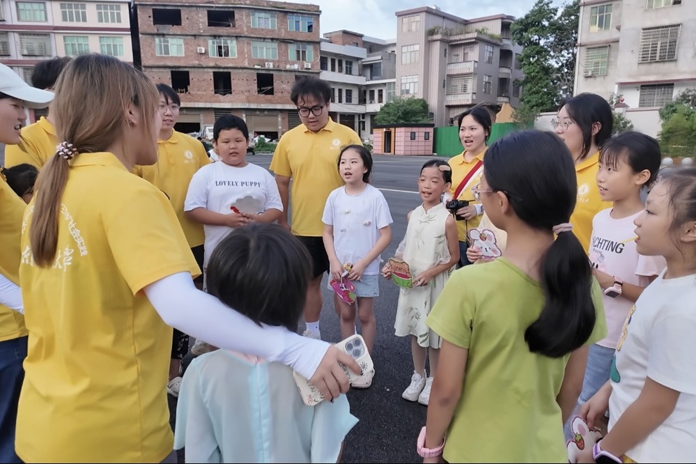 图1：队员与小朋友手拉手围成圆圈，共同合唱《萱草花》