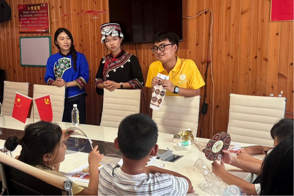 图1：图为实践队员站于台前，为现场乡镇孩童讲解土家织锦与民族服饰文化