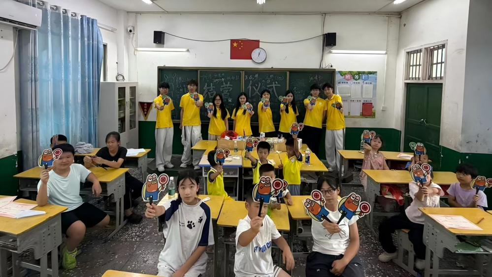 图为祁心协力实践团成员与学生在黑板上留名纪念